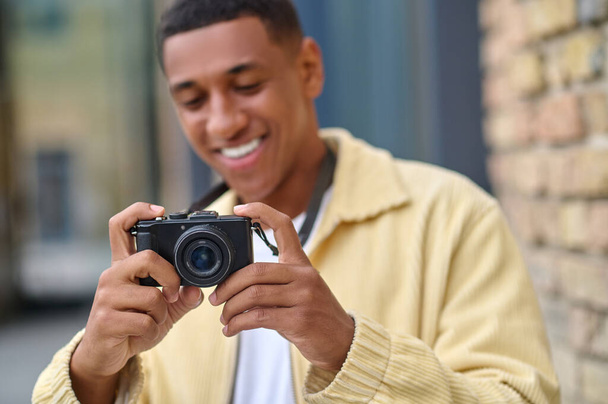 Positive photographer with camera in hands looking happy - Fotó, kép