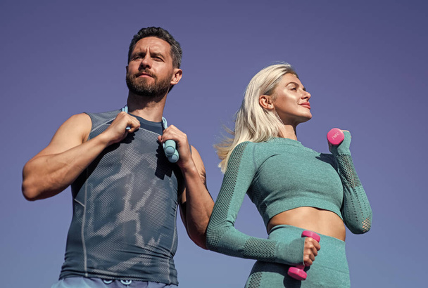 sport couple in sportswear training with barbells and skipping rope on sky background, fitness - Foto, Imagem