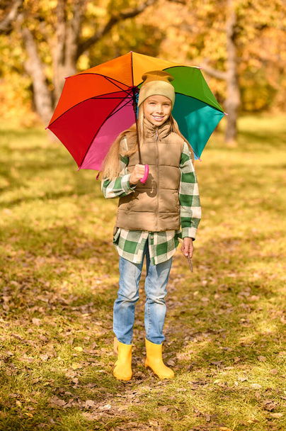 Una ragazza con un ombrello luminoso in un parco autunnale - Foto, immagini