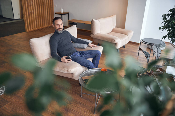 Glücklich erwachsener männlicher Geschäftsmann sitzt und chillt in gemütlichen Büroräumen - Foto, Bild