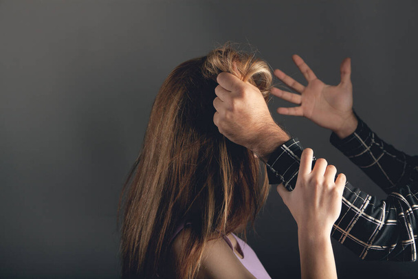 the husband is holding his wife by the hair. domestic violence - Фото, зображення