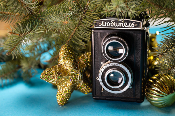 black retro camera with Christmas decorations on a blue background. - Foto, afbeelding