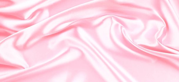Beautiful pastel pink background with drapery and wavy folds of silk satin material texture. Top view - Foto, immagini