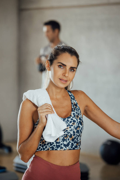 Πορτρέτο της αυτοπεποίθηση νεαρή γυναίκα στέκεται στο γυμναστήριο κοιτάζοντας κάμερα.  - Φωτογραφία, εικόνα