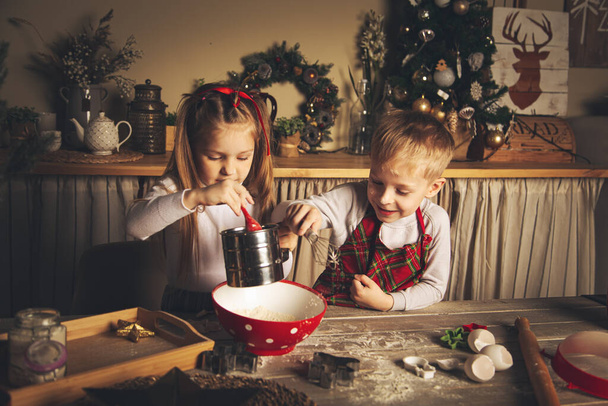 Children in the kitchen are preparing cookies. Christmas decorations, family traditions, Christmas food, holiday eve.  - Fotoğraf, Görsel