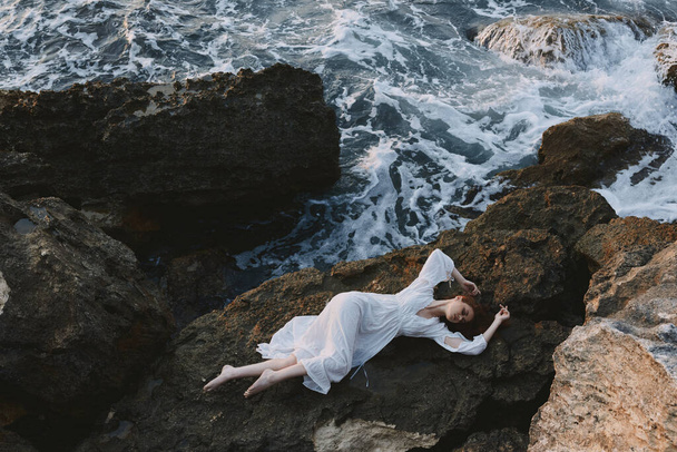 Bela noiva em vestido branco longo cabelo molhado deitado em um penhasco rochoso conceito de férias de verão - Foto, Imagem