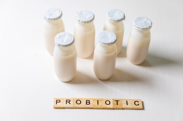 Botellas pequeñas con probióticos y prebióticos bebida láctea sobre fondo blanco. Producción con aditivos biológicamente activos. Fermentación y dieta de alimentos saludables. Yogur bio con microorganismos útiles. - Foto, Imagen
