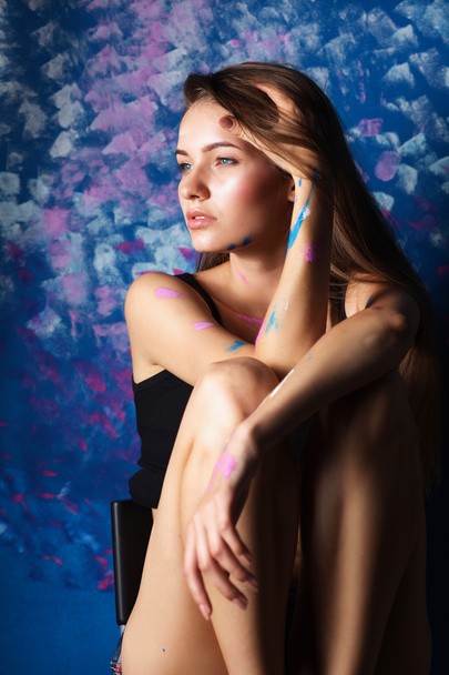 Young woman sitting near painting wall - Photo, image