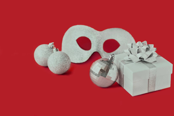 Karnaval maskesi, hediye kutusu ve Noel baloları yılbaşı karnavalı nitelikleri. Kırmızı arkaplanda fotokopi alanı olan yeni yıl özellikleri. Şenlikli Yeni Yıl afişi. - Fotoğraf, Görsel