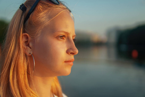 blonde teen girl standing on the lake at sunset. - Фото, изображение