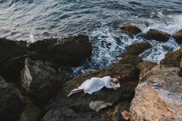 Frau im weißen Kleid auf einem Stein liegend im weißen Kleid Sommerferienkonzept - Foto, Bild