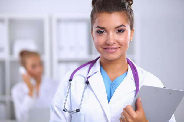 Smiling female doctor with a folder in uniform standing at hospital - Fotografie, Obrázek