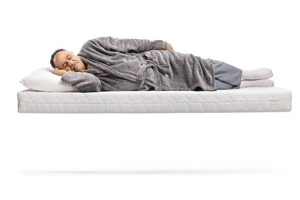 Mature man sleeping on a matress and floating isolated on white background - Zdjęcie, obraz