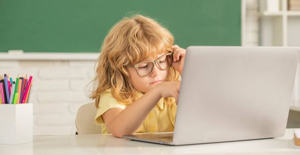 Okulda gözlüklü çocuk bilgisayar ve okulla çevrimiçi çalışıyor. - Fotoğraf, Görsel