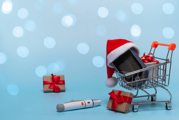 Kosz z glukometrem na kolorowym tle z podświetleniem. Boże Narodzenie koncepcja zakupów online, aptek i sprzedaży plus prezent. Zbliżenie z miejsca kopiowania - Zdjęcie, obraz