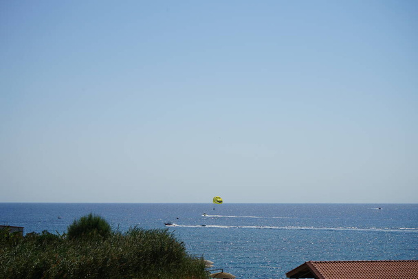Parasailing en el Mediterráneo. Parasailing es una actividad recreativa de kite donde una persona es remolcada detrás de un vehículo mientras está atada a un ala de dosel especialmente diseñada que se asemeja a un paracaídas, conocido como ala de parasail. Rodas, Grecia  - Foto, imagen