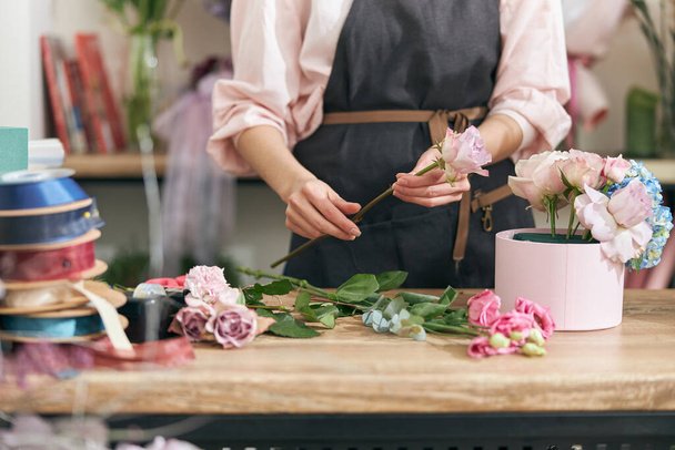 Professional florist young woman is doing bouquets at flower shop - Photo, Image