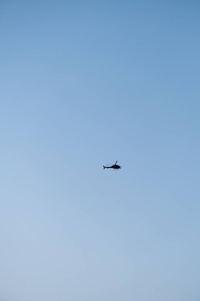 Helicopter flying in the blue sky. Helicopter silhouette in the sky. Flying - Foto, immagini