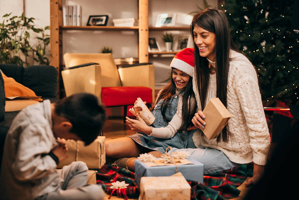 Szczęśliwa rodzina siedzi razem w święta Bożego Narodzenia i przygotowuje prezenty świąteczne. - Zdjęcie, obraz