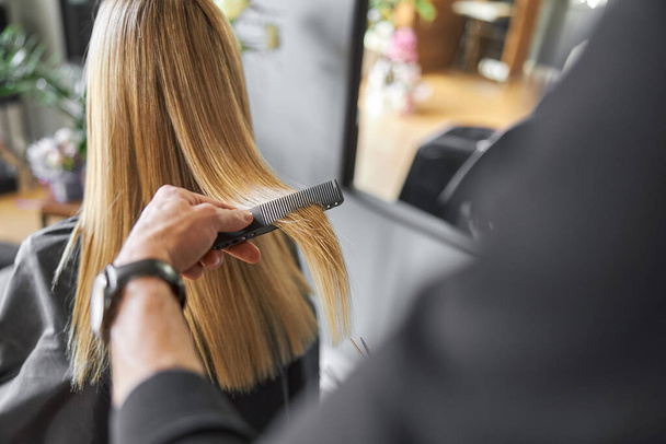 Hairdresser is choping hair of blonde woman is salon - Fotoğraf, Görsel