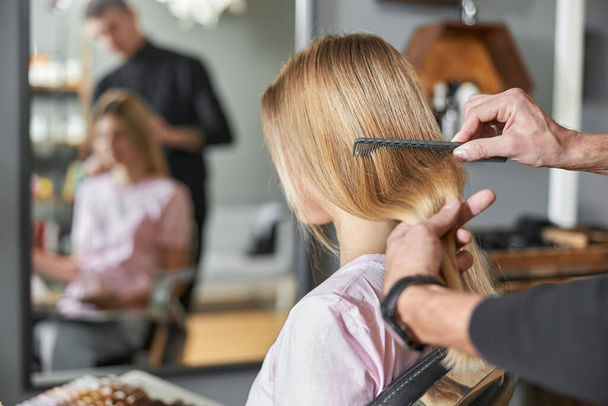 Pofessional kadeřnice je česání vlasy krásné kavkazské blondýny v moderním salonu - Fotografie, Obrázek