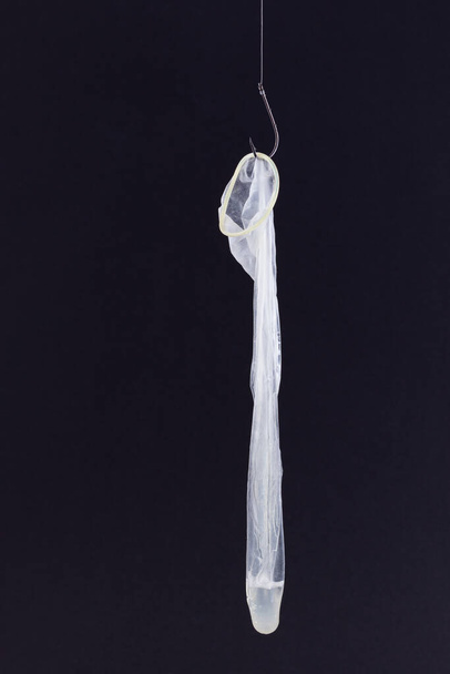 Used Condom with Sperm Inside is Hanging on a Fishing Hook - Fotografie, Obrázek