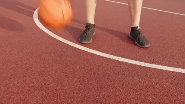 Jambes d'homme faisant de l'exercice avec ballon de basket, entraînement de basket en plein air, suivi de caméra - Séquence, vidéo