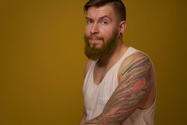 Cheerful bearded man in a white T-shirt with hooligan tattoos on his arms - Fotoğraf, Görsel