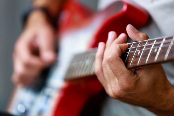 Gitar, müzisyen bir gitaristin elinde odak dışı. Metin veya harf için kopyalama alanı olan bir arkaplan. Seçici odak - Fotoğraf, Görsel
