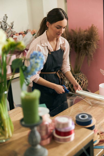Florista profesional mujer joven está haciendo ramos en la tienda de flores - Foto, Imagen