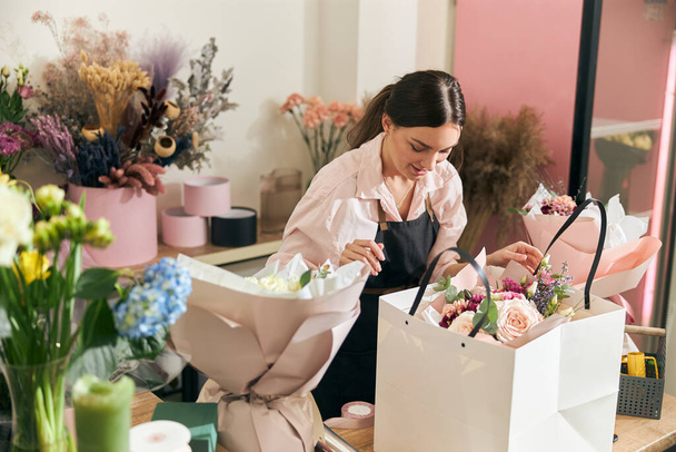 Профессиональный флорист молодая женщина делает букеты в цветочном магазине - Фото, изображение