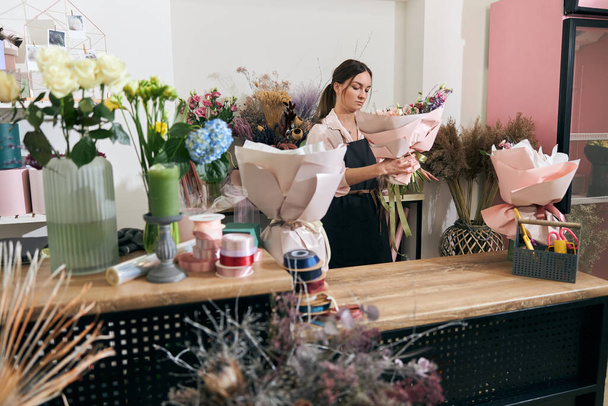 Florista profesional mujer joven está haciendo ramos en la tienda de flores - Foto, Imagen