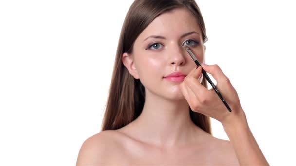 Hermosa mujer aplicando maquillaje sobre fondo blanco
 - Imágenes, Vídeo