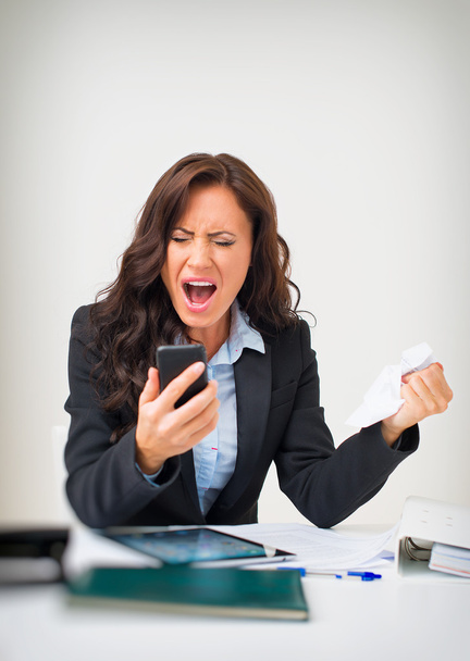 Mujer de negocios enojada con teléfono en la oficina
. - Foto, Imagen