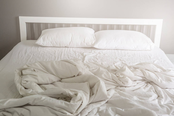 Две белые подушки на кровати с морщинистым грязным одеялом на заднем плане спальни - Фото, изображение