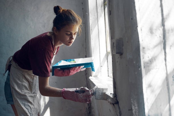 woman painter paints window with brush renovation interior decoration - Foto, imagen