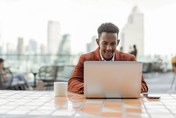Retrato de empresário africano ao ar livre em café usando computador portátil - Foto, Imagem