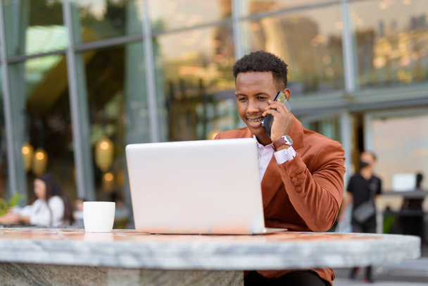 Retrato de empresário africano ao ar livre em café usando computador portátil - Foto, Imagem