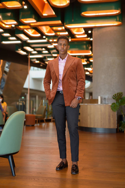 Black stylish African businessman standing in coffee shop full length shot - Photo, image