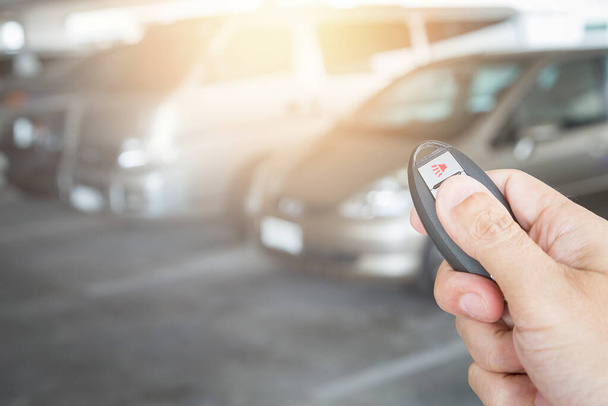 Hand holding car key remote at car park background - Фото, изображение