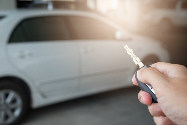 Рука держит ключ от машины на заднем плане парковки - Фото, изображение