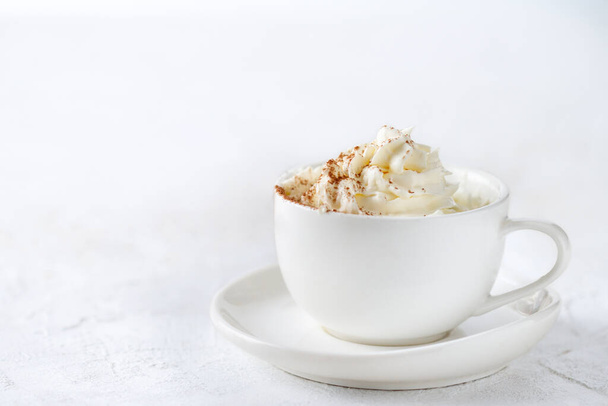 Drink in a white mug with whipped cream on a white plate, copy space - Фото, изображение