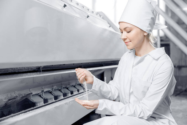 Nainen operaattori tarkistaa valmiiden elintarvikkeiden laadun. Nykyaikaiset sähkömyllykoneet vehnäjauhon valmistukseen - Valokuva, kuva