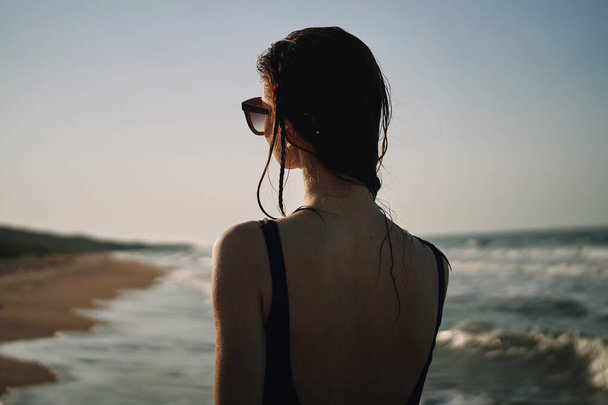 woman in black swimsuit walking on the beach ocean summer - Фото, изображение