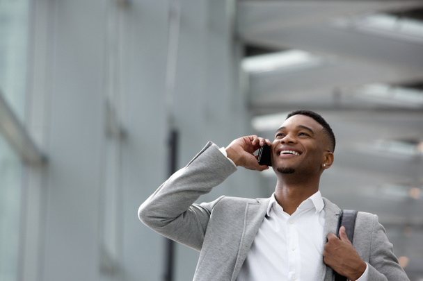 Happy young man talking on mobile phone inside building - Photo, Image