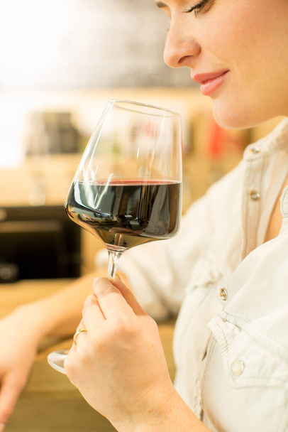 Joven mujer atractiva, degustación de vino en una tienda de vinos, disfrutando de una copa de sabroso vino tinto o blanco - Foto, Imagen