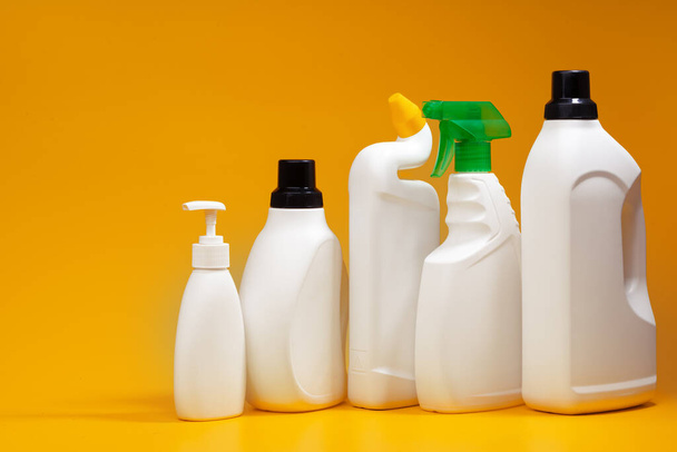 Huisreiniging reinigingsmiddel flessen op een gele achtergrond - Foto, afbeelding