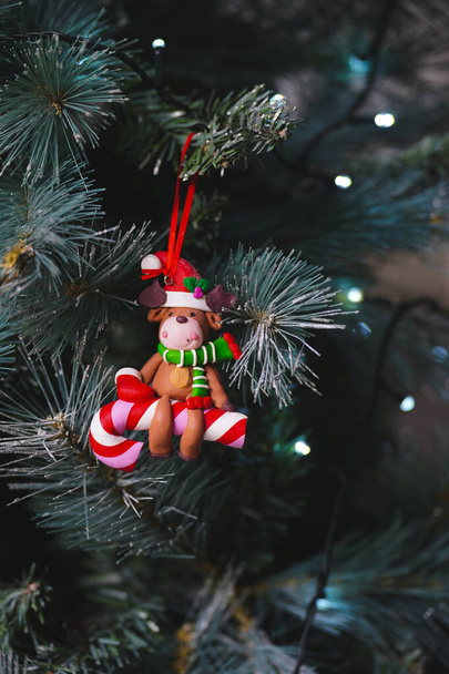 Karácsonyi dekoráció egy rénszarvast ábrázol egy karácsonyfán lógó cukornádon. - Fotó, kép