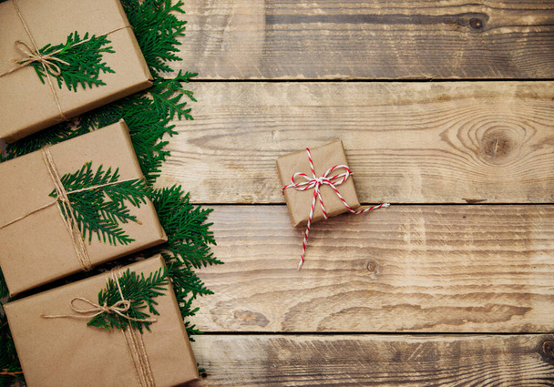 Boxes packed in kraft paper and green branches on a wooden background. Sale. Environmentally friendly material.Christmas and New Year. - Foto, Imagen