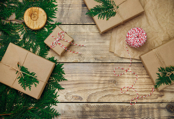 Boxes packed in kraft paper and green branches on a wooden background. Sale. Environmentally friendly material.Christmas and New Year. - Foto, Imagen